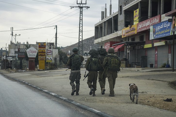 Des soldats israéliens patrouillent dans une ville palestinienne, complètement vidée après que l'armée israélienne ait fermé les commerces et banni les véhicules palestiniens de la route principale. © KEYSTONE/AP/Mahmoud Illean